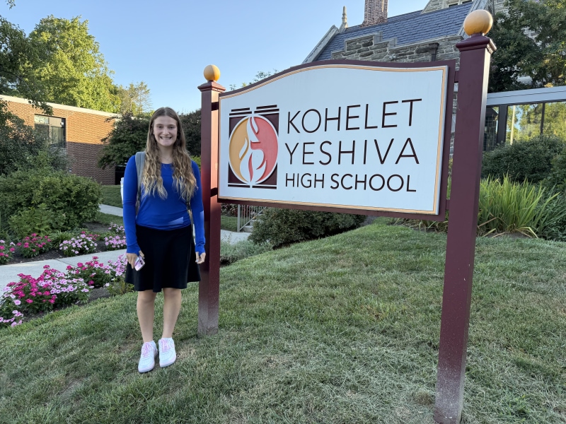 Student posing by high school sign