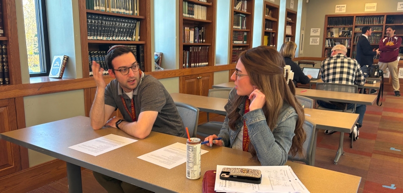 Two adults discussing at desk